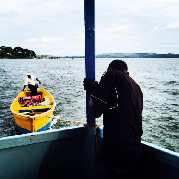 A man helps tie a canoe to a ferry enroute the shores of Lake Victoria in Kampala, Uganda. March 2015. Photo by @edward_echwalu